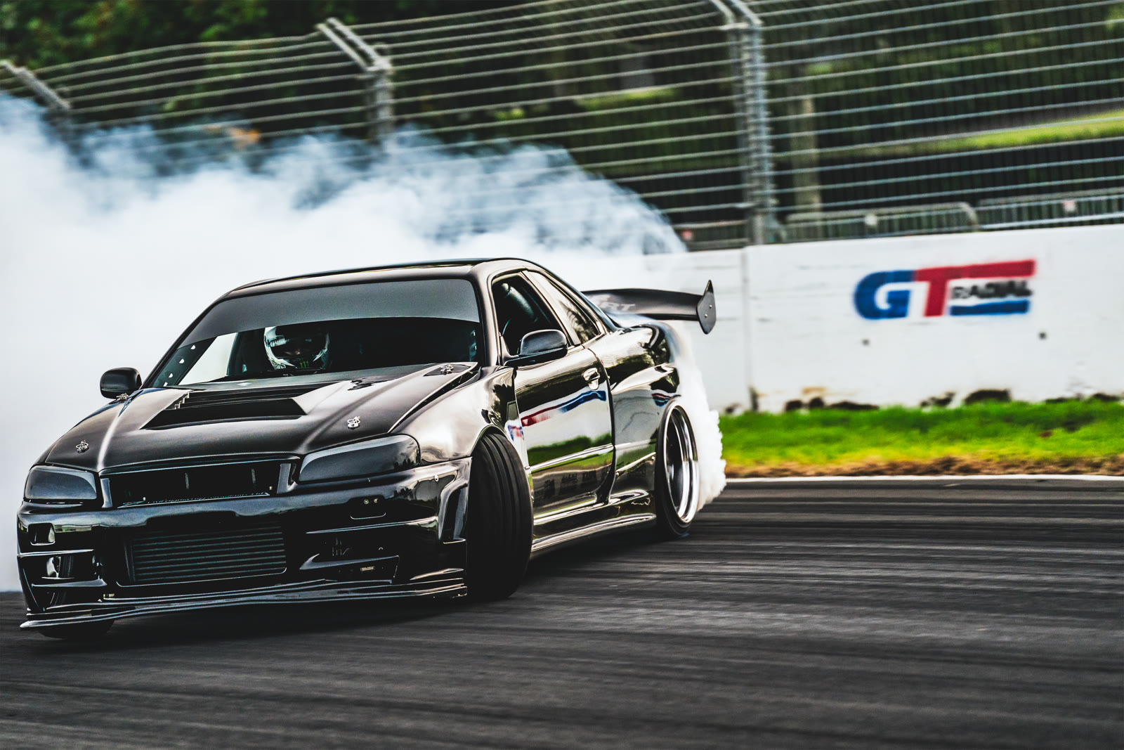 A drift car sliding past the GT Radial trackside banner
